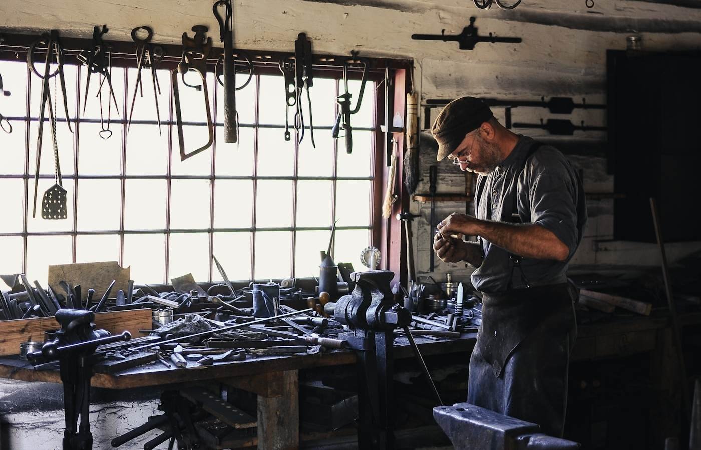 A tradesperson working at a bench in a tool-lined workshop