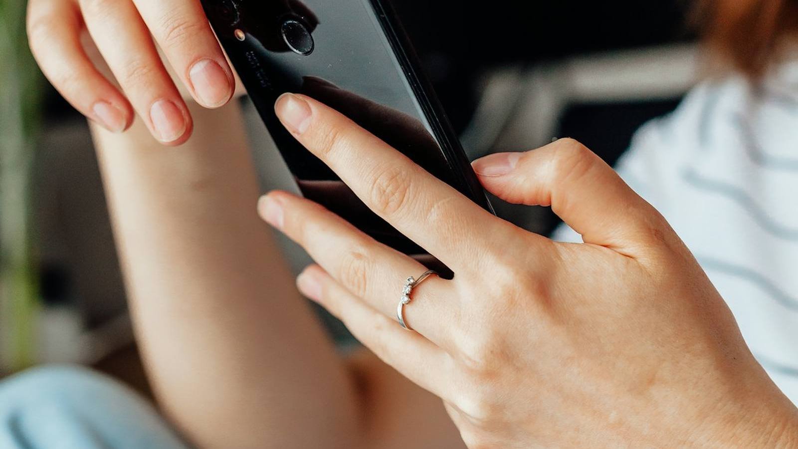 A hand scrolling a phone in low light