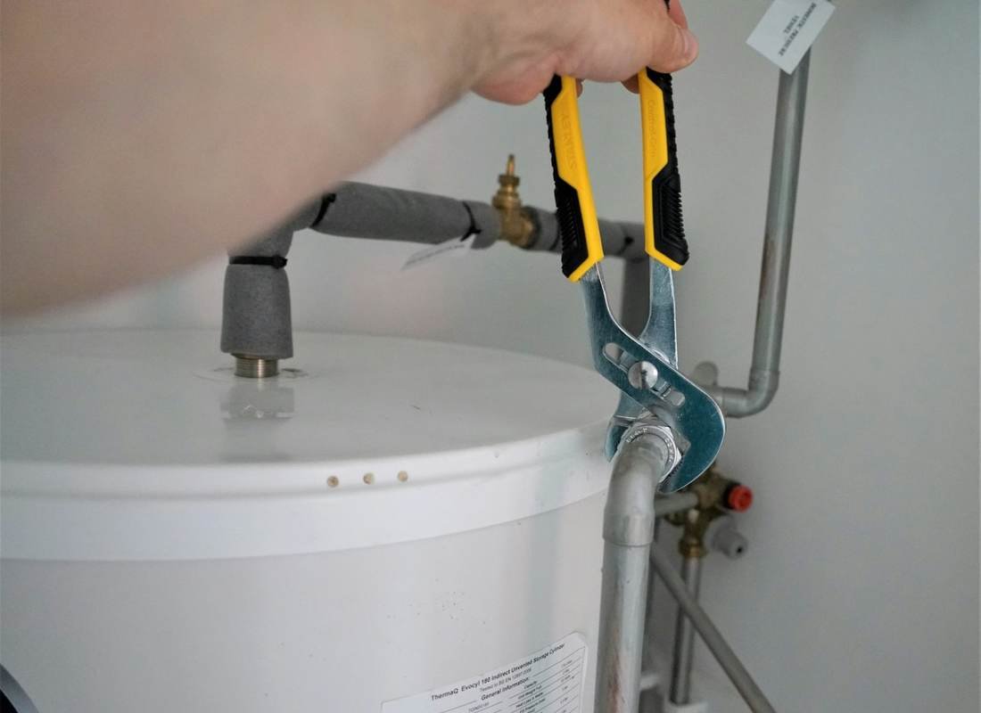 Hands fitting a wrench to an external hot water system