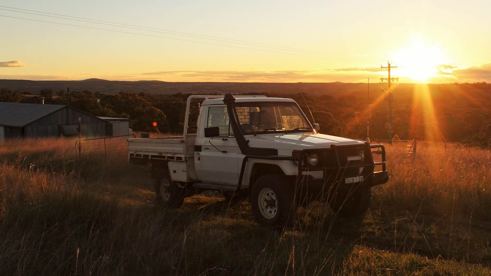 A work ute parked on a track at dusk in dry country